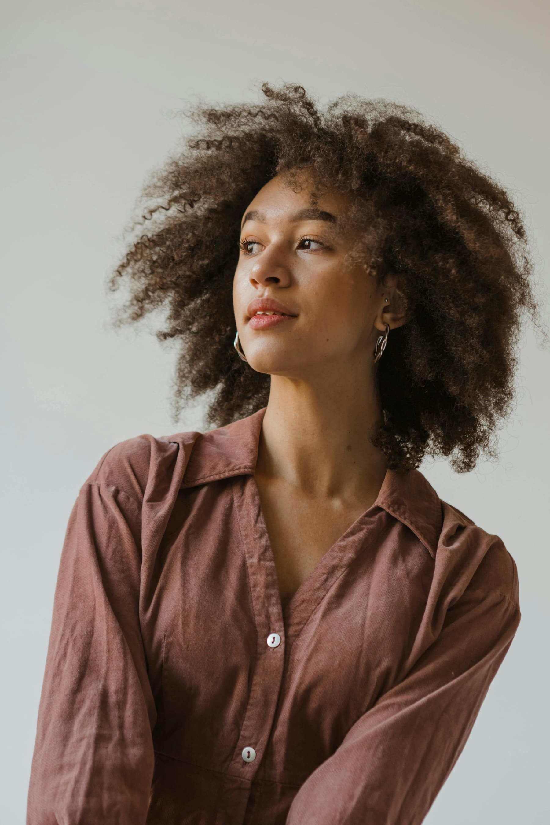 Woman with curly hair looking upward, thoughtful editorial portrait